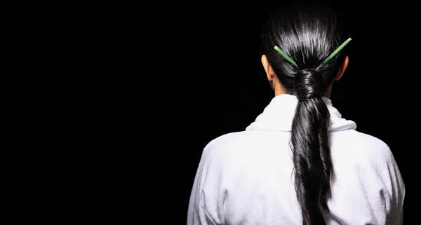 Woman with long dark hair and a restrained botanical hair accent.