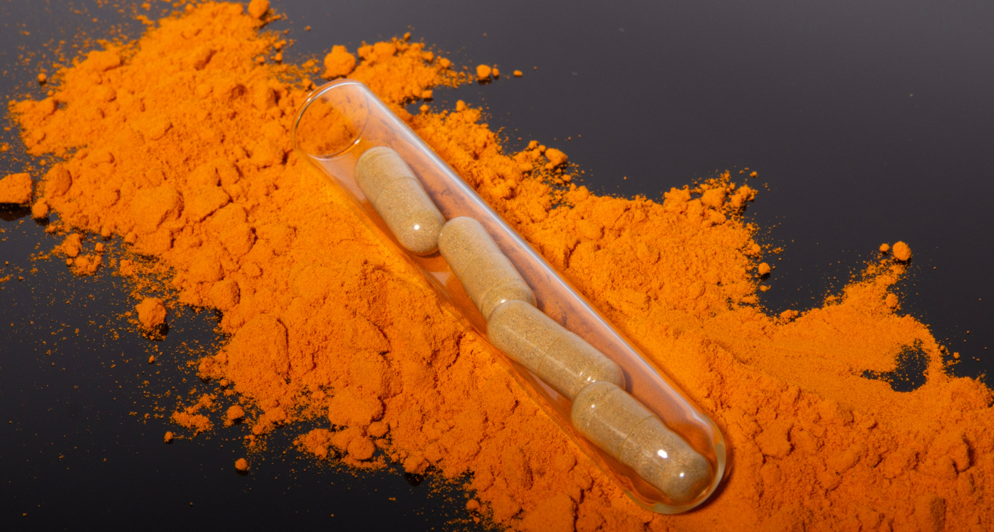 Turmeric supplement for hair loss capsules resting on golden spice powder, rich in curcumin for hair growth and scalp health.