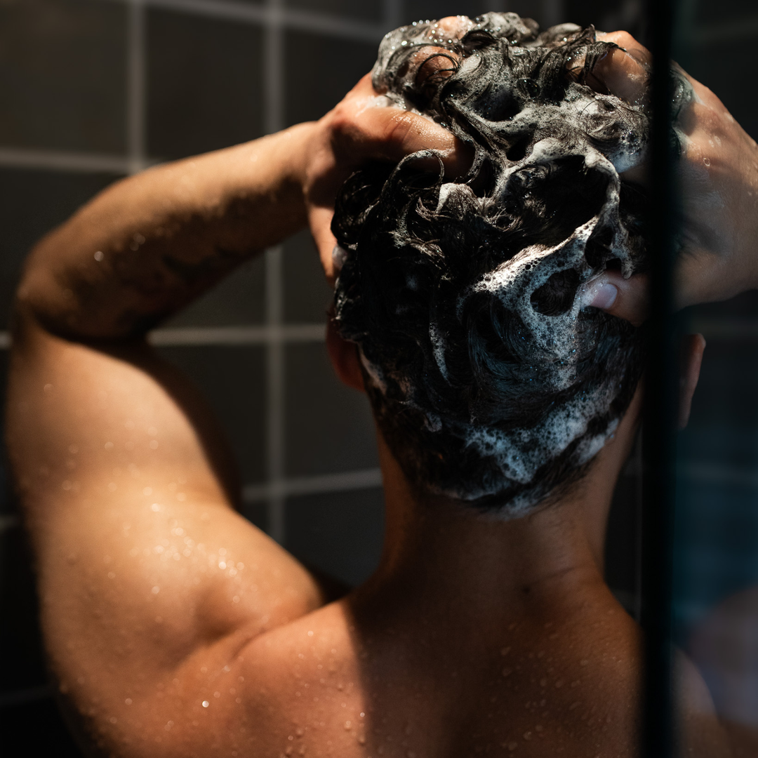 Male washing his hair in the shower.