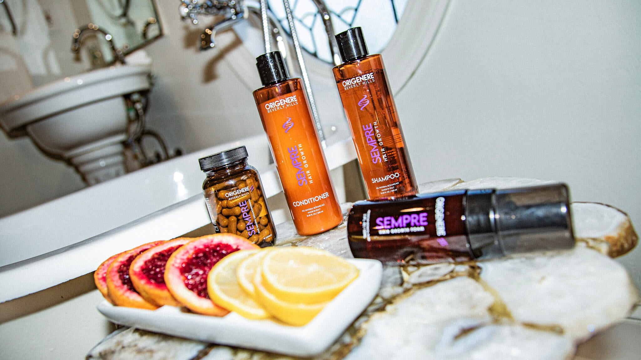 Sempre Hair Growth collection: shampoo, conditioner, vitamins and foam artfully displayed next to citrus slices and a bath tub.