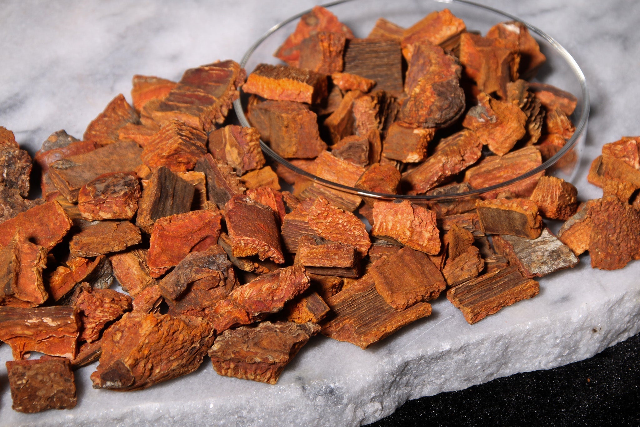 Cinchona succirubra bark in glass bowl overflowing onto marble table 