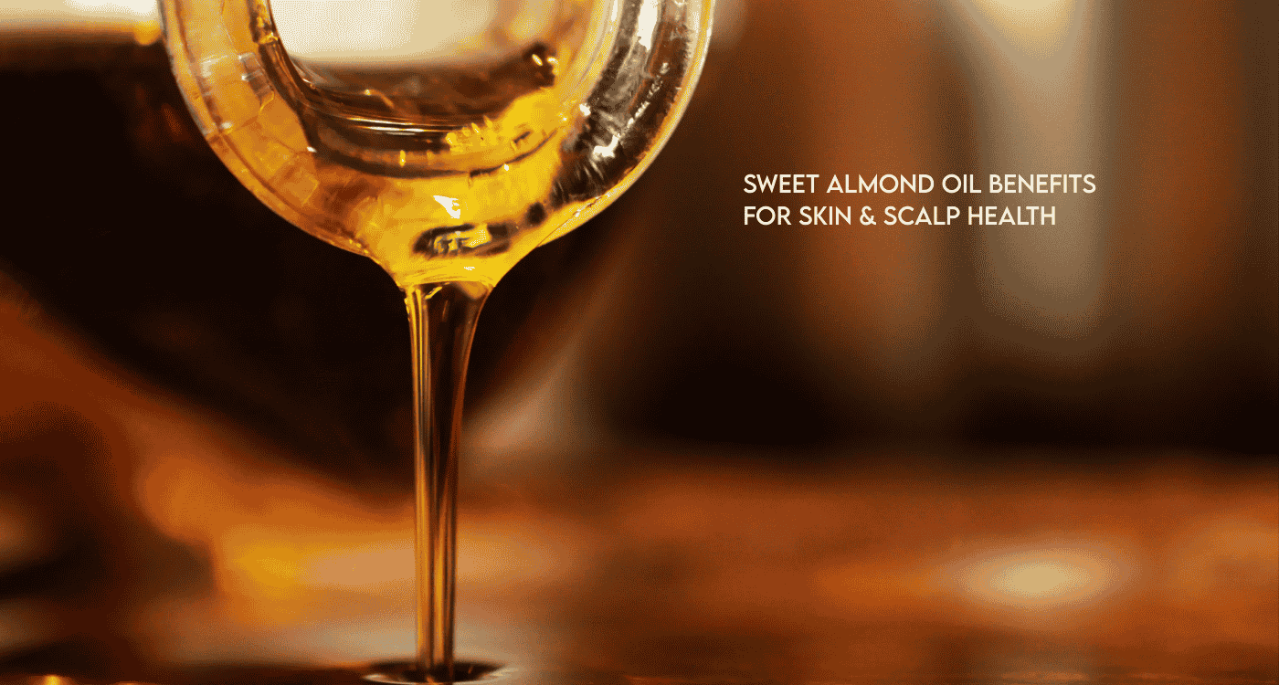 Golden sweet almond oil pouring from a glass vessel, illustrating sweet almond oil benefits for skin and scalp health.