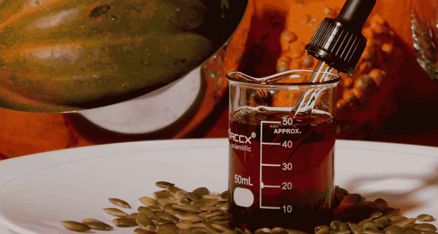 Pumpkin seed oil in scientific beaker with pumpkin seeds – rich in essential fatty acids like linoleic and oleic acid, shown to support hair regrowth, scalp health, and female hair loss treatment – Origenere Sempre Hair Growth Organonutrients ingredient