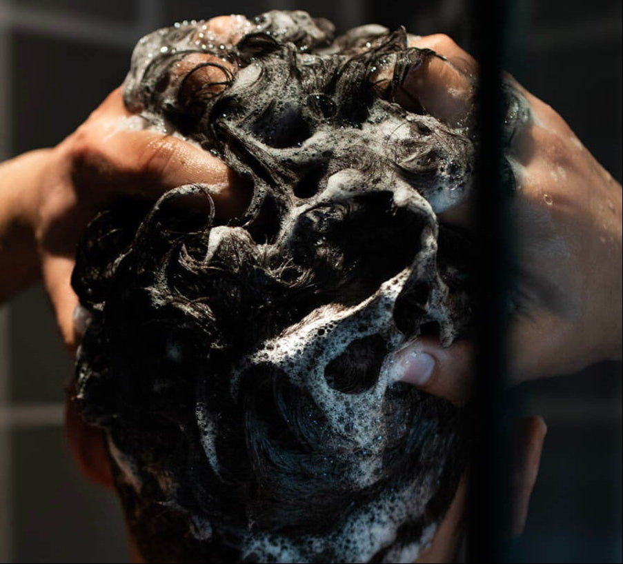 Male washing thick hair in shower 